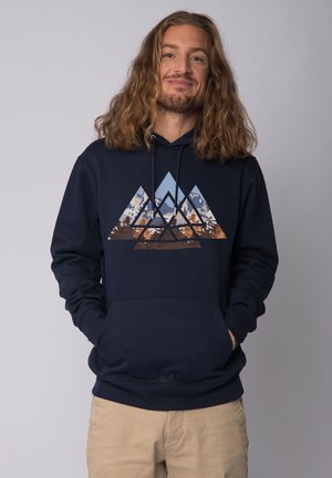 Donkerblauwe hoodie van katoen; heeft een driehoekige bergafbeelding in tinten blauw, oranje en bruin. Voorzien van een kangoeroezak.