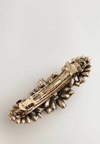 Agrafă de păr vintage din metal de aur cu un design floral texturat și mecanism de prindere, pe un fundal deschis.