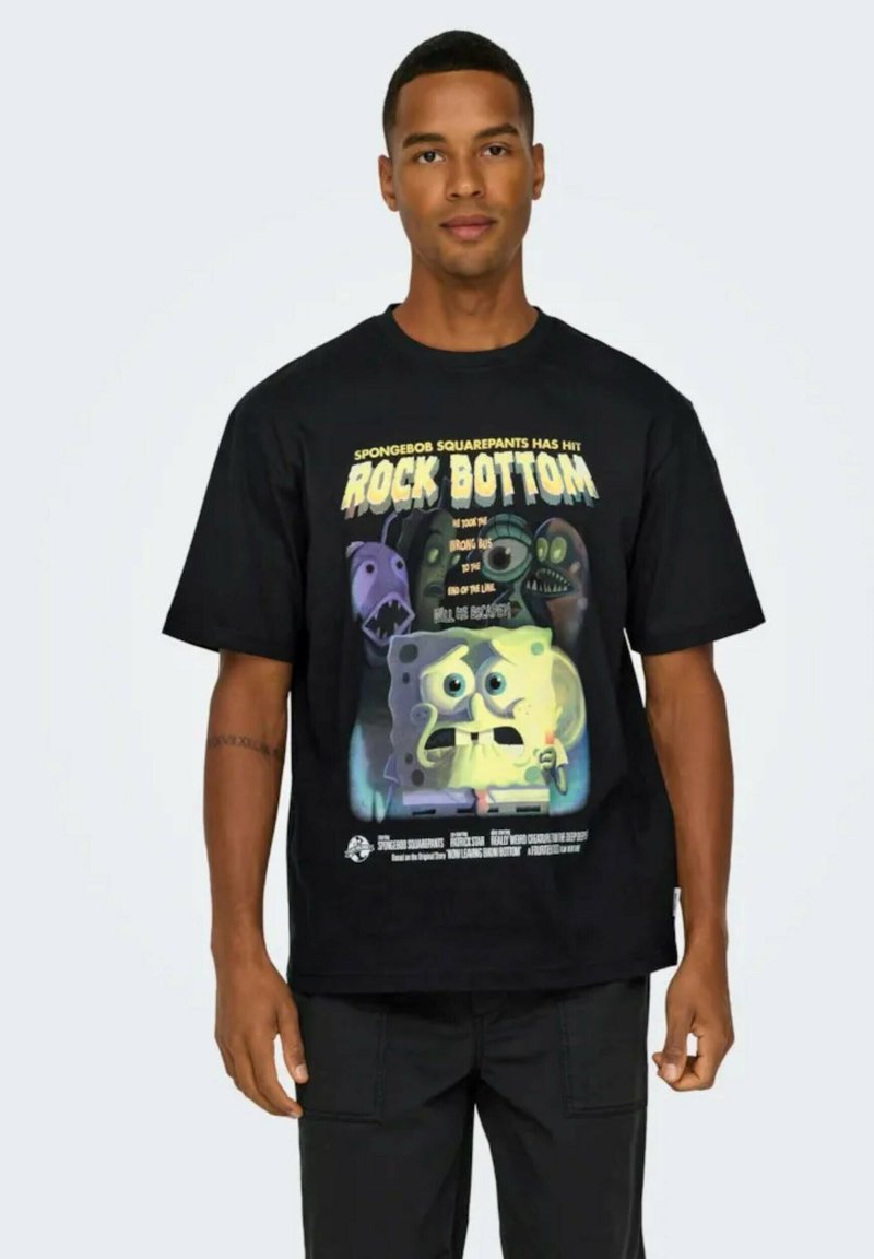 Camiseta de algodón negra con una impresión gráfica de Bob Esponja, con el texto "Rock Bottom" y diversas criaturas subacuáticas en colores vibrantes.