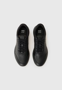 Zapatillas deportivas negras con un upper de cuero liso, detalles perforados y acentos texturizados. Cuentan con cordones planos y plantillas acolchadas.