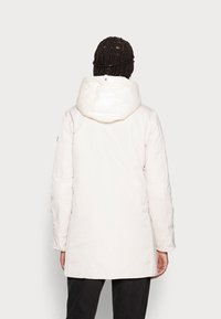 Biała pikowana kurtka z kapturem, o gładkiej fakturze i dłuższym kroju. Zawiera detale szwów i kieszenie po bokach.