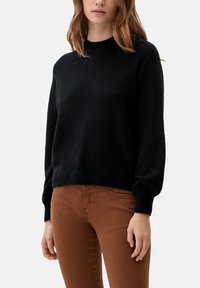 Zwart gebreid sweater met een ronde halslijn en lange poffende mouwen, gecombineerd met bruine, aansluitende broek. Zachte textuur en comfortabele pasvorm.