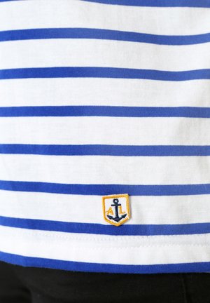 T-shirt en coton rayé bleu et blanc avec un logo d'ancre brodé dans un écusson jaune au bas. Manches courtes, col rond.