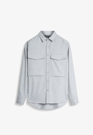 Chemise boutonnée grise claire en tissu texturé. Comprend deux poches poitrine et un col classique. Manches longues avec poignets boutonnés.