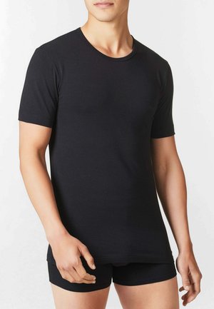 T-shirt nera con scollo rotondo realizzata in tessuto elastico e morbido, con maniche corte e vestibilità aderente, abbinata a pantaloncini neri.