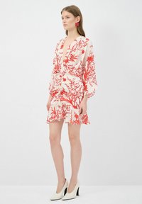 Rood bloemenprint jurk met korte mouwen, gemaakt van lichtgewicht stof, met een V-hals, wikkelontwerp en uitlopende zoom, gecombineerd met witte hoge hakken.