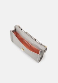 Grå læder clutch med en glat overflade, der har en orange inderside, guldfarvet hardware og en tryklås. Indvendig lomme til organisering.