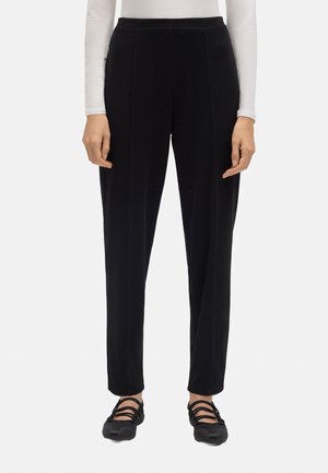 Pantalones negros de talle alto con un corte ajustado, que presentan una textura suave, costuras verticales y un diseño de pierna recta. Combinados con zapatos negros.