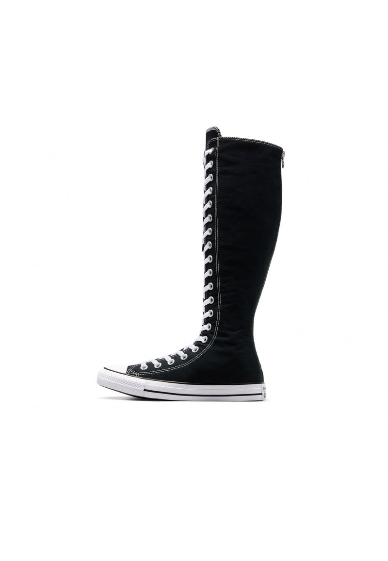 Tênis de cano alto pretos com um design alto, feitos de lona. Apresentam atacadores brancos, costura e uma sola de borracha com biqueira.