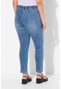 Světl�é modré jeansy z denimu s elastickým pasem, pěticípým designem a slim fit, doplněné černými platformovými sandály.