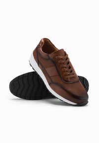Bruine leren sportschoenen met een textuurafwerking, geperforeerd ontwerp en witte zool; met een ronde neus en zes oogjes voor veters.