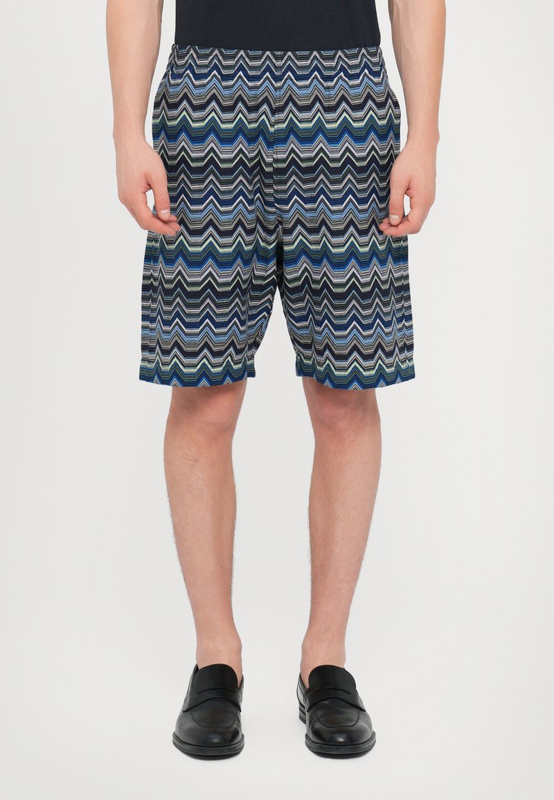 Herrsim shorts i ett zigzagmönster av blått, grönt och svart. Tillverkade av lättviktigt material, med elastisk midja och sidofickor.