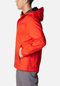 Rote wasserdichte Jacke mit Kapuze, Reißverschluss vorne, Seitentaschen und elastischen Bündchen. Leichter Stoff mit glatter Textur.