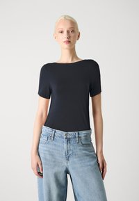 T-shirt court bleu marine à manches courtes avec un col bateau arrondi, associé à un jean large bleu clair, doté d'un design classique à cinq poches.