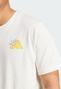 White cotton t-shirt featuring a yellow graphic with "The Classic" text. Classic crew neck and short sleeves. Soft texture.