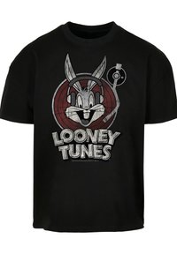 Črna bombažna majica s grafiko risanega zajca, ki nosi slušalke, z napisom "Looney Tunes" v krepki beli barvi spodaj.