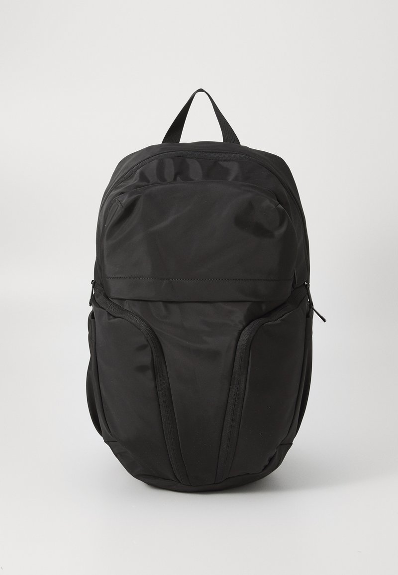 Zaino in nylon nero con due tasche laterali, maniglia superiore e finitura liscia. Presenta un scomparto principale con zip e un design minimalista.