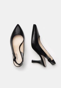 Scarpe alte nere in pelle con punta affusolata e fianchi tagliati. Presentano un design slingback con un tacco texturizzato e dettagli decorativi.