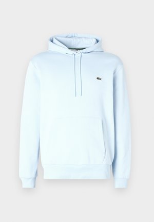 Sweat à capuche bleu clair avec poche kangourou à l'avant et petit logo crocodile vert sur la poitrine.
