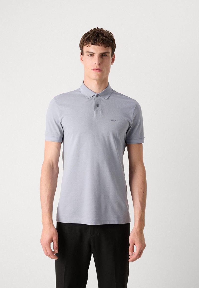 Hellgrau Polo-Shirt aus Baumwolle, mit klassischem Kragen, drei Knöpfen und dezenter Logodetailierung auf der Brust. Kurze Ärmel.