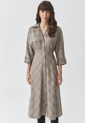 Langes, knielanges Kleid mit einem braun- und cremefarbenen Karomuster. Es verfügt über einen kragenlosen Ausschnitt, Dreiviertelärmel und eine taillierte Passform.