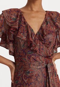 Kleid mit einem Paisleymuster in warmen Rot- und Purpurtönen, mit Rüschensämlen und einem tiefen V-Ausschnitt, tailliert mit einem gebundenen Gürtel.
