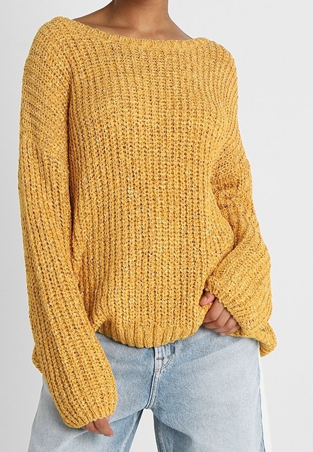 Mustard yellow knitted sweater with a wide neckline, loose long sleeves, and ribbed cuffs, paired with light blue high-waisted jeans.