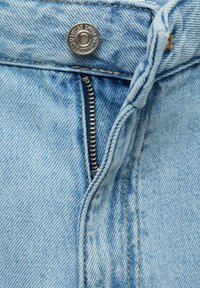 Light blue denim jeans featuring a metal button closure, zipper fly, and contrasting tan stitching along the seams.