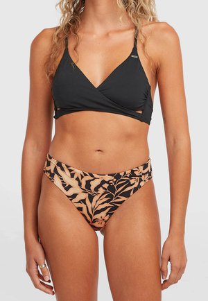 Naine, kes kannab musta bikiinikatet õhukeste rihmadega ja lillemustriga bikiinipõhja toonides virsiku ja musta.