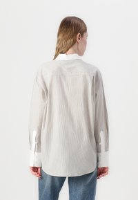 Lichte, gestreepte shirt met lange mouwen, voorzien van een witte kraag en knoopjesmanchetten. Zachte textuur, relaxte pasvorm en afgeronde zoom.