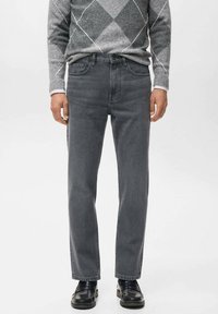 Jeans de mezclilla gris con corte recto y diseño clásico de cinco bolsillos, combinados con un suéter gris de patrón y zapatos negros.