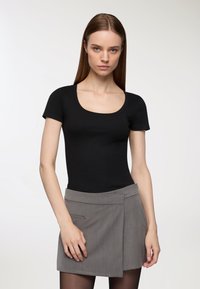 Czarny, prążkowany bodysuit z krótkim rękawem i okrągłym dekoltem, w połączeniu z szarą, owijaną mini spódnicą z bocznymi kieszeniami i gładką teksturą.