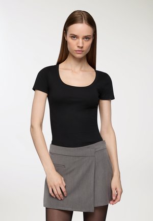 Body nero a maniche corte con righe e scollatura a barca, abbinato a una mini gonna grigia avvolgente con tasche laterali e una texture liscia.