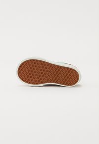 Chaussure à semelle en caoutchouc avec une semelle extérieure texturée et à motifs. Le design présente un contour blanc et un dessus multicolore avec des accents vifs.