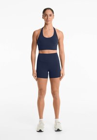 Marinblått träningsset tillverkat av slät, elastisk tyg; innehåller en åtsittande sportbh med racerback och högmidjade shorts.