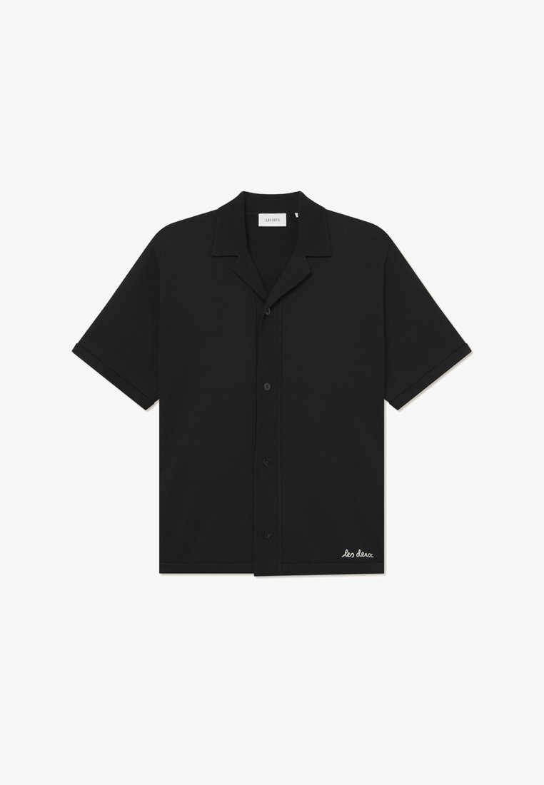 Lyhythihainen musta paita, joka on valmistettu pehmeästä kankaasta. Paidassa on kauluskansi, nappiosa edessä ja brodeerattu logo helman kohdalla.