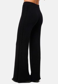 Pantalons larges noirs avec un motif en câble texturé sur le côté. Fabriqués en tissu doux avec une taille élastique pour le confort.