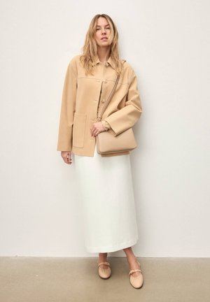 Beežikas ülisuur jakk nööpidega, valge maksiseelik ja heledabeezid lamedad kingad pandlakinnitusega. Lihtne käekott, nähtavad siledad tekstuurid.