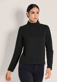 Schwarzer Kabelstrickpullover mit hohem Kragen, langen Ärmeln und strukturiertem Muster; aus weichem, dehnbarem Stoff gefertigt.
