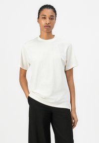 White short-sleeve t-shirt with a crew neck and subtle embossed logo on the chest. Made from a smooth fabric, it offers a relaxed fit.