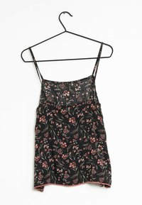 Svart blommig linne med tunna axelband, med rosa blommönster och en slät yta, upphängd på en svart galge.