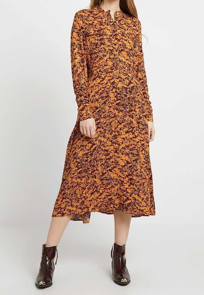 Abito midi a maniche lunghe arancione con motivo astratto nero, realizzato in un tessuto leggero, con colletto button-down e vestibilità comoda.