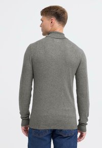 Grå sweater med høj krave, lange ærmer og ribstrikkede manchetter. Lavet af et blødt, tekstureret stof, med en tætsiddende pasform.