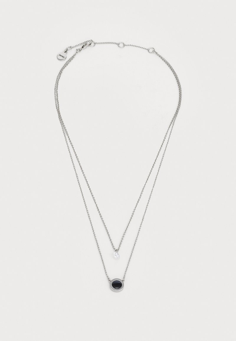 Colar em tom prateado com duas correntes sobrepostas. Apresenta um pendente circular preto e um pequeno detalhe em pedra preciosa clara. Comprimento ajustável.