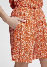 Oranje met patronen short heeft een elastische tailleband, zijzakken en een relaxte pasvorm van een lichtgewicht stof.