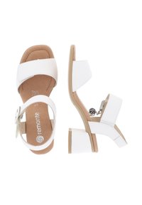 White heeled sandals with two wide straps and an ankle strap. Made of smooth material, featuring a textured insole and a chunky heel.