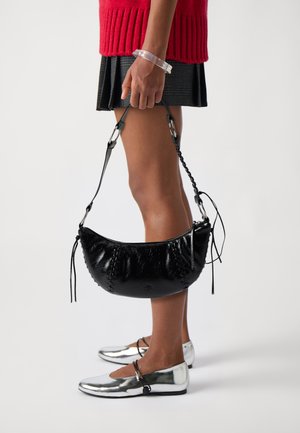 Must kafest mustra kott, millel on punutud õlarihm ja kontrastsete õmbluste detailid, koos hõbedaste tasaste kingadega.