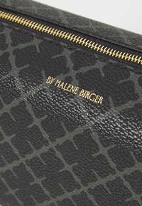 Black textured leather pouch with a subtle embossed pattern and a gold zipper. Branding is printed in gold, situated on the front.