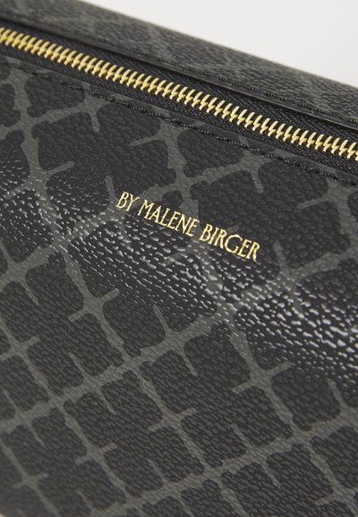 Melna teksturēta ādas soma ar smalku reljefa rakstu un zelta rāvējslēdzēju. Zīmols ir attēlots zeltā un atrodas priekšpusē.