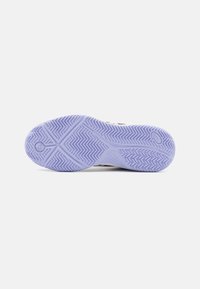 Sula på en sneaker med ett lila zigzag-mönster och cirkulära logotypformer på en vit bakgrund.